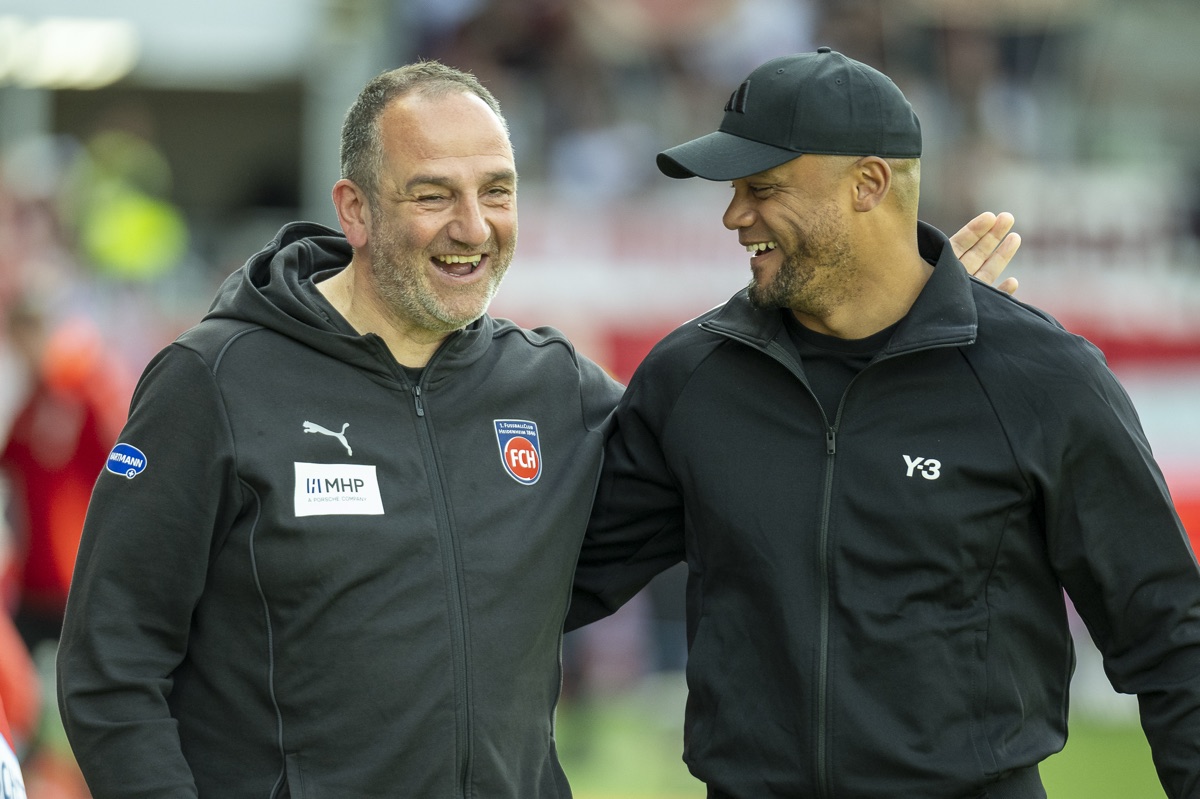 Zwei Trainer im Gespräch, lachend am Spielfeldrand